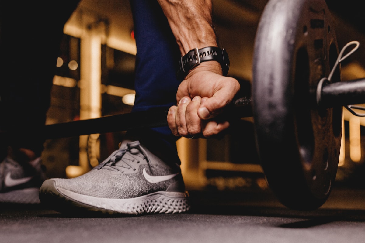 A close-up of a hand gripping a loaded barbell in a gym